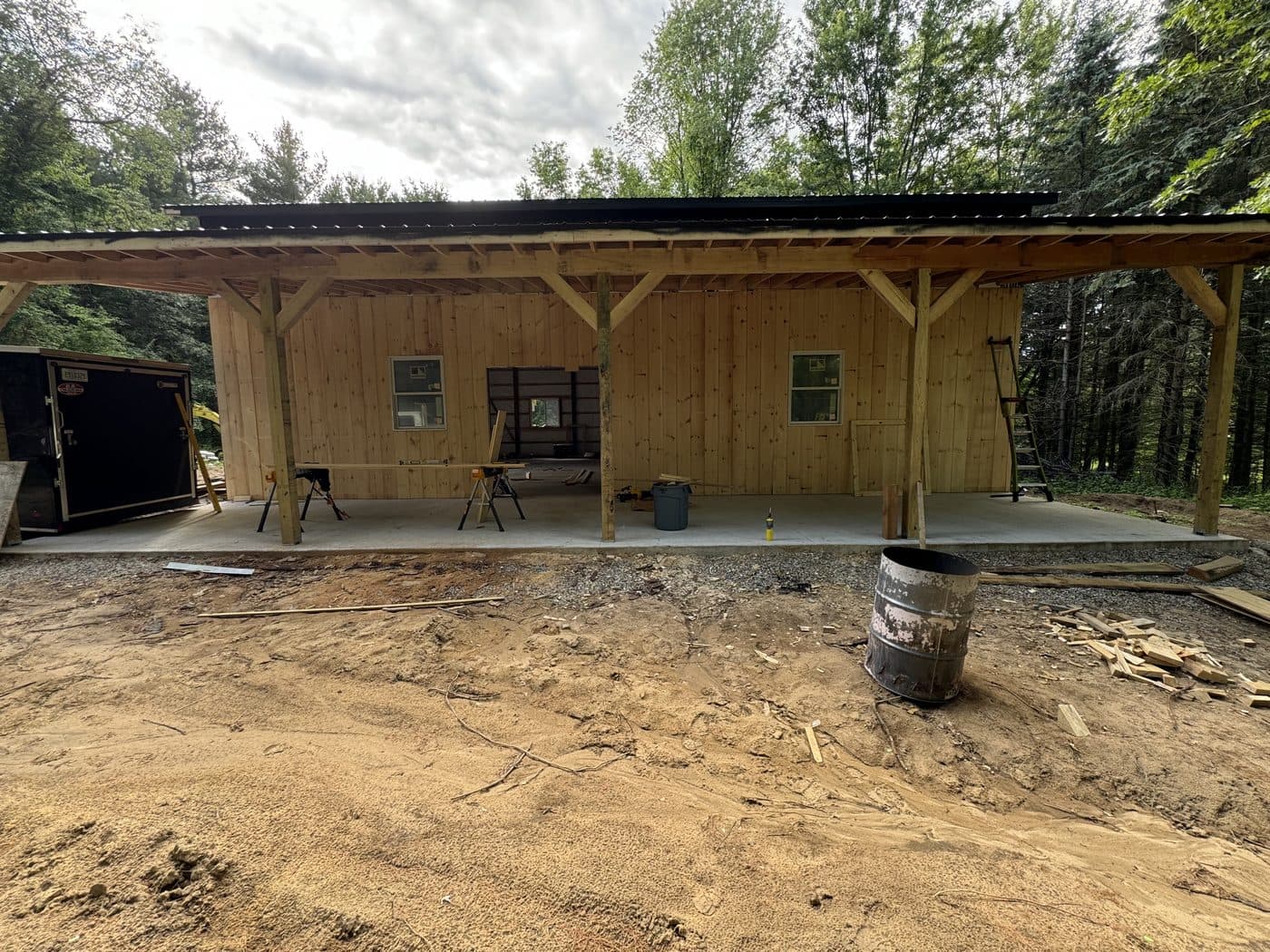 Timber-frame covered porch under construction on a fresh concrete pad